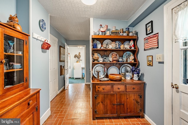 corridor featuring brick patterned flooring, baseboards, and an ornate ceiling
