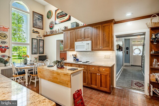 kitchen featuring white appliances, decorative backsplash, brown cabinets, and baseboards
