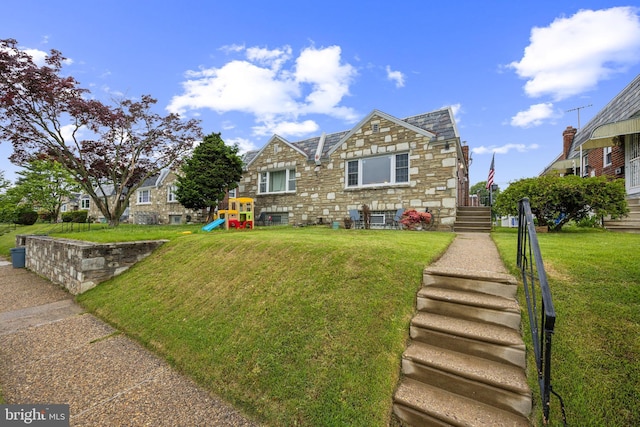 view of front facade featuring stone siding, a front lawn, and a playground