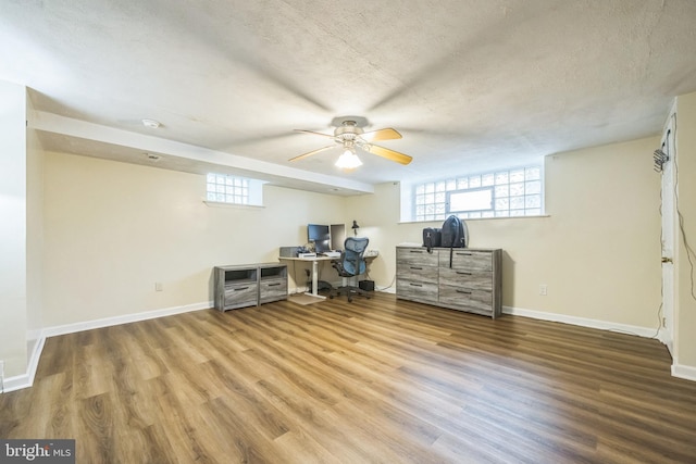 office featuring wood finished floors, ceiling fan, plenty of natural light, a textured ceiling, and baseboards