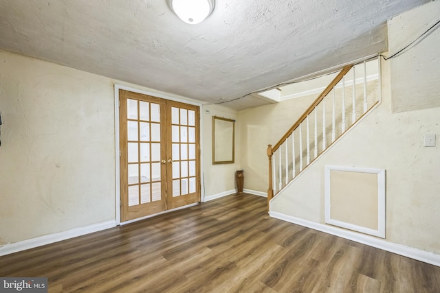 unfurnished living room featuring wood finished floors, french doors, baseboards, and stairs