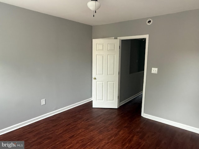 empty room featuring dark wood-type flooring and baseboards