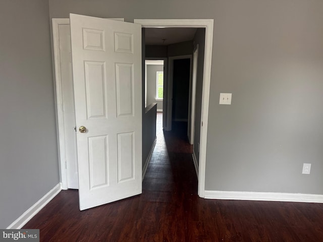 hall featuring baseboards and dark wood-style floors