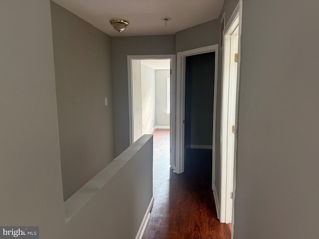 hallway with dark wood-type flooring and baseboards