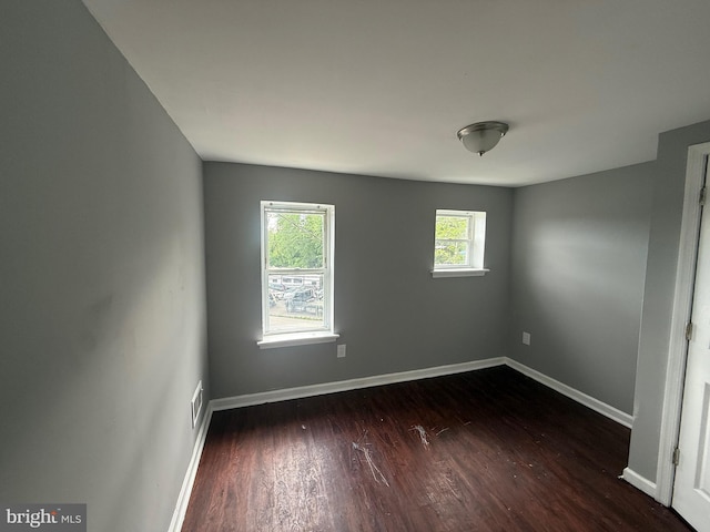 unfurnished room featuring dark wood-type flooring and baseboards