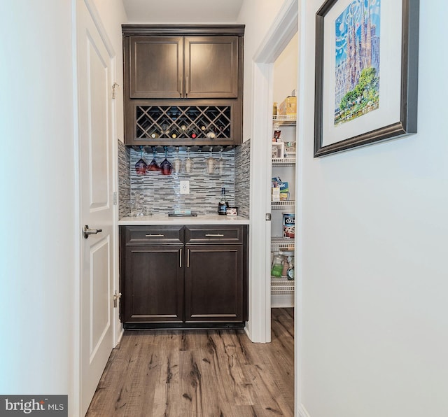 indoor dry bar with tasteful backsplash and light wood-style flooring
