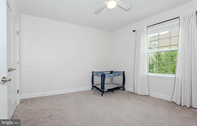 carpeted empty room featuring baseboards and a ceiling fan