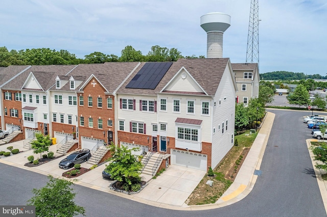 view of building exterior with an attached garage, concrete driveway, and stairs