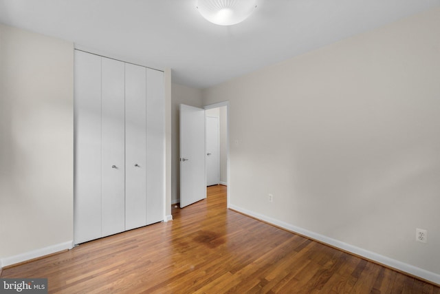 unfurnished bedroom featuring baseboards, light wood-style floors, and a closet