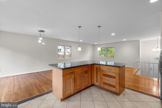 kitchen featuring healthy amount of natural light, dark stone countertops, decorative light fixtures, and recessed lighting