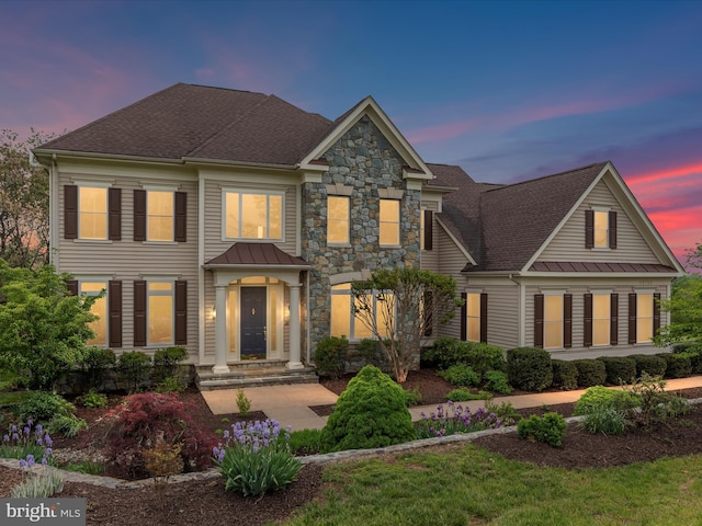 view of front of property featuring a standing seam roof, a shingled roof, stone siding, and metal roof