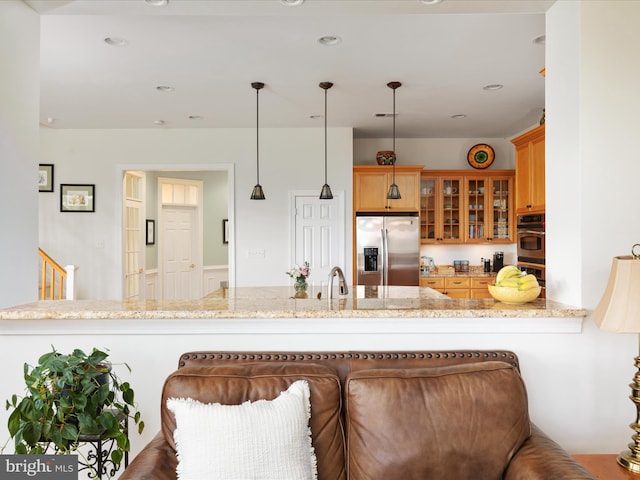 kitchen featuring stainless steel appliances, a peninsula, glass insert cabinets, light stone countertops, and hanging light fixtures