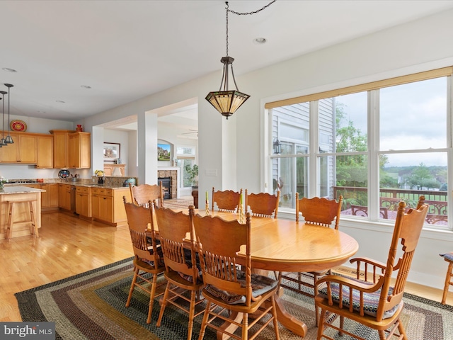 dining area featuring plenty of natural light, light wood-style flooring, a glass covered fireplace, and recessed lighting