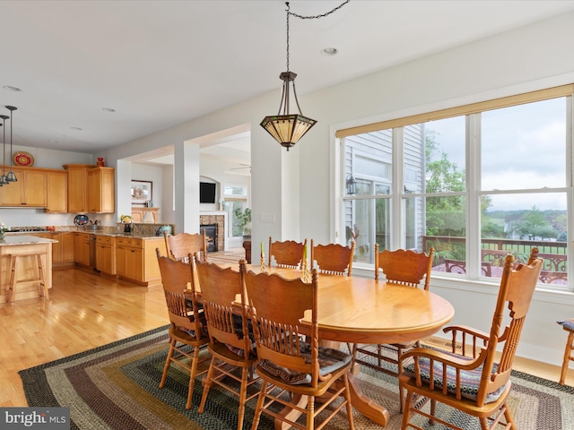 dining space featuring plenty of natural light, light wood-style floors, a glass covered fireplace, and recessed lighting