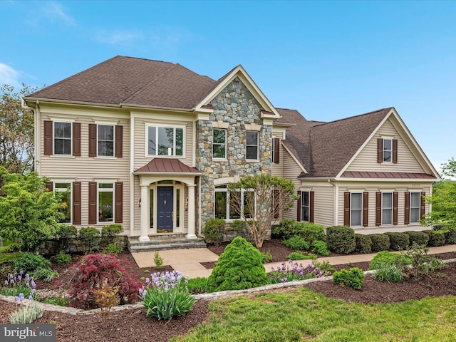 view of front of home with a standing seam roof, roof with shingles, stone siding, and metal roof