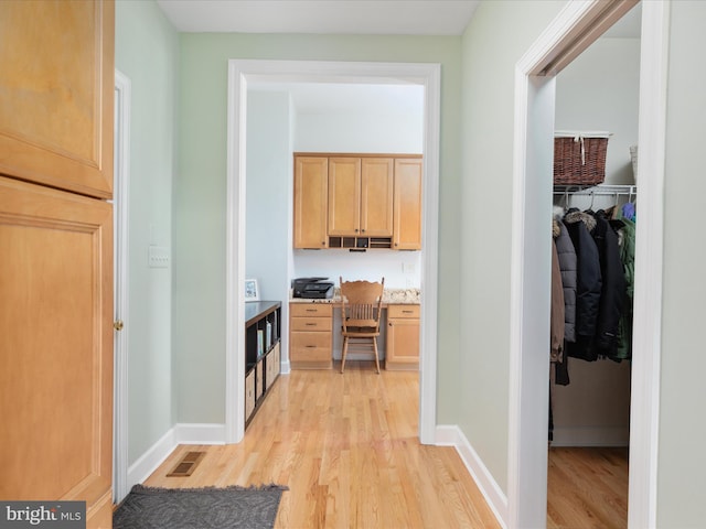 hall featuring light wood-style flooring and baseboards
