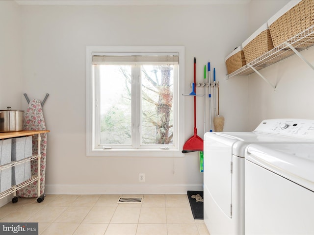 clothes washing area with separate washer and dryer, baseboards, and light tile patterned floors