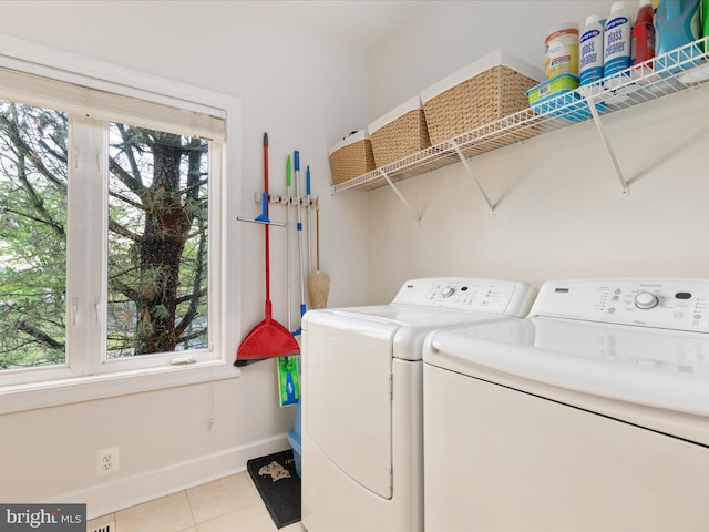 clothes washing area featuring separate washer and dryer, light tile patterned floors, baseboards, and plenty of natural light