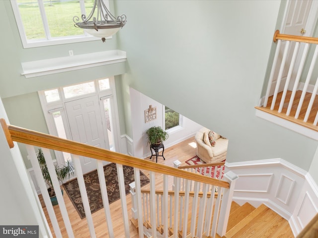 stairway with wood finished floors, plenty of natural light, and a chandelier