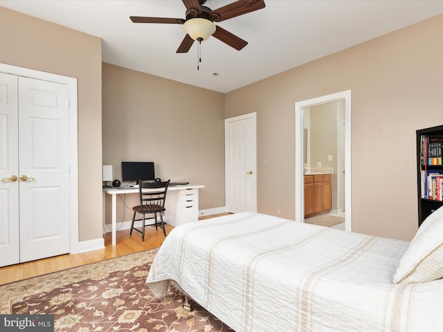 bedroom with light wood-style flooring, baseboards, a desk, connected bathroom, and a ceiling fan