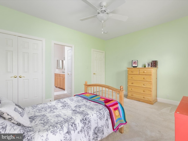 carpeted bedroom featuring a closet, baseboards, ensuite bath, and a ceiling fan