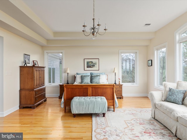 bedroom featuring a chandelier, light wood-type flooring, and baseboards
