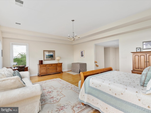 bedroom featuring a chandelier, light wood finished floors, and baseboards