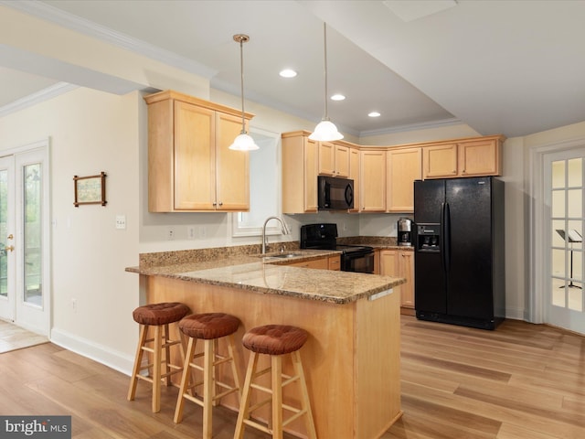 kitchen with black appliances, light brown cabinetry, ornamental molding, a peninsula, and a sink