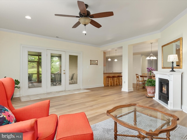 living area featuring ornamental molding, wood finished floors, ceiling fan, baseboards, and french doors