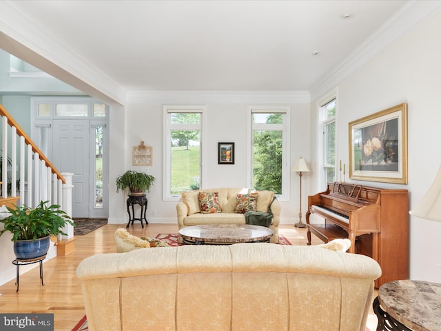 living area with ornamental molding, light wood-style flooring, and stairs