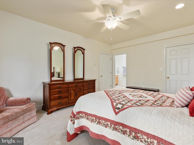 bedroom featuring light colored carpet, connected bathroom, a ceiling fan, and baseboards