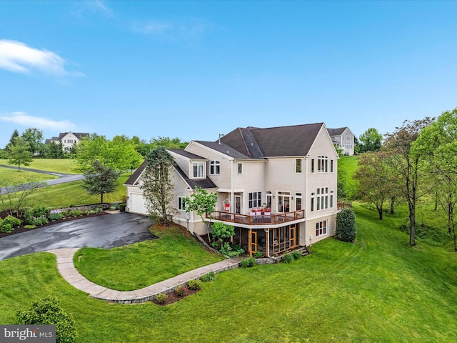 back of property with a lawn, driveway, and a garage