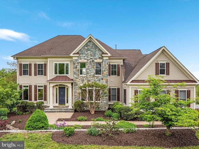 view of front of home with a standing seam roof, stone siding, a shingled roof, and metal roof