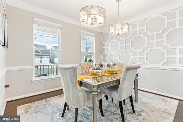 dining room featuring a chandelier, ornamental molding, wood finished floors, and baseboards