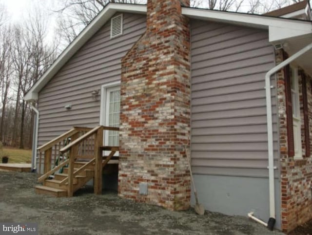 view of side of home with a chimney and brick siding