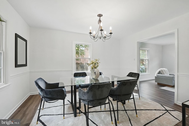 dining space featuring a chandelier, wood finished floors, and baseboards