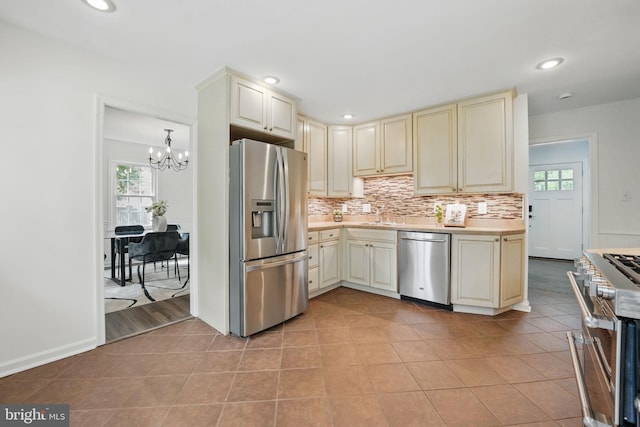 kitchen featuring stainless steel appliances, cream cabinets, a chandelier, light countertops, and recessed lighting