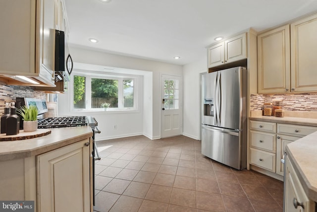 kitchen featuring appliances with stainless steel finishes, cream cabinets, backsplash, light countertops, and light tile patterned floors