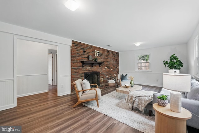 living area with wood finished floors, a fireplace, and wainscoting