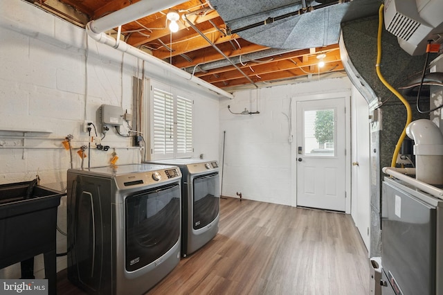 washroom featuring washer and clothes dryer, wood finished floors, and concrete block wall
