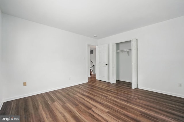 unfurnished bedroom featuring dark wood finished floors, baseboards, and a closet
