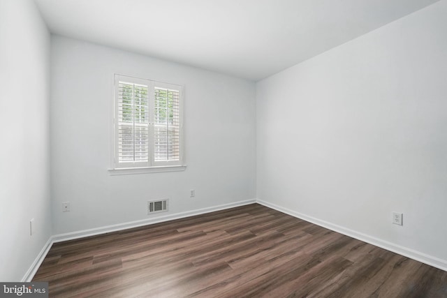 empty room with dark wood-type flooring and baseboards