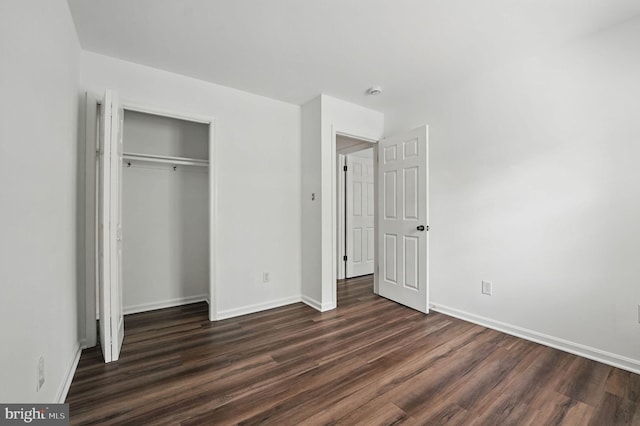 unfurnished bedroom with dark wood-type flooring, baseboards, and a closet