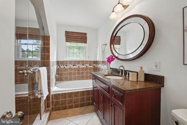 bathroom featuring tile patterned flooring, vanity, a garden tub, and toilet