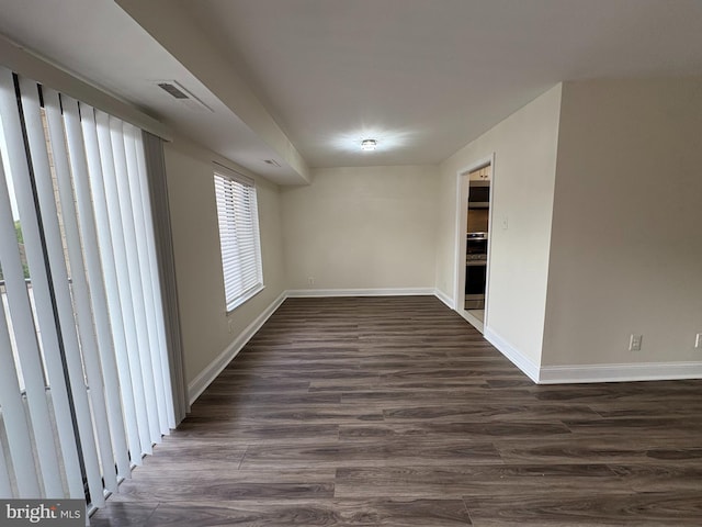 spare room featuring dark wood-type flooring and baseboards