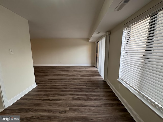 corridor with dark wood-style flooring and baseboards