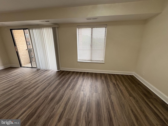 unfurnished room featuring baseboards and dark wood finished floors