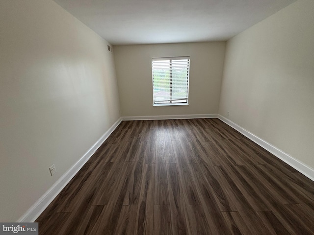 spare room with dark wood-style flooring and baseboards