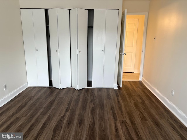 unfurnished bedroom with baseboards and dark wood-style floors