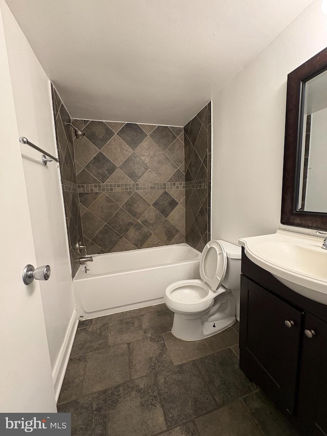 bathroom featuring toilet, shower / tub combination, vanity, baseboards, and stone finish flooring